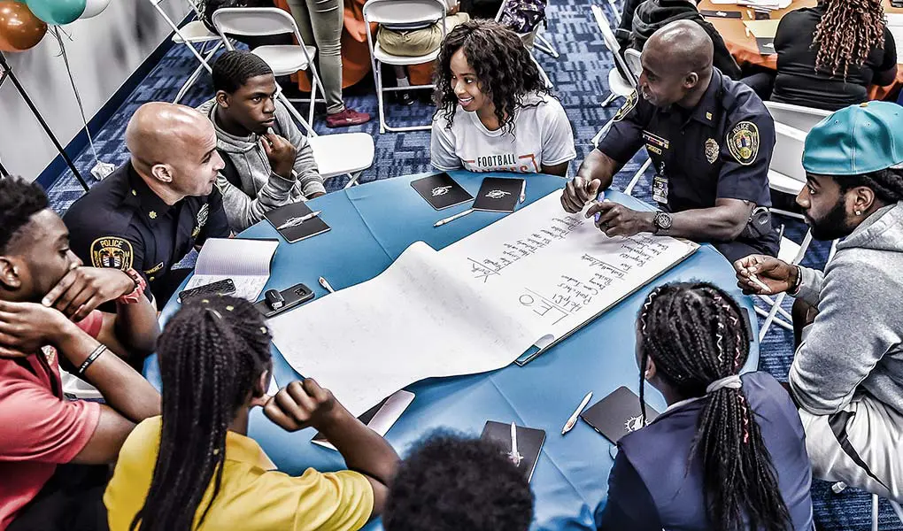 people at a table talking with police officers